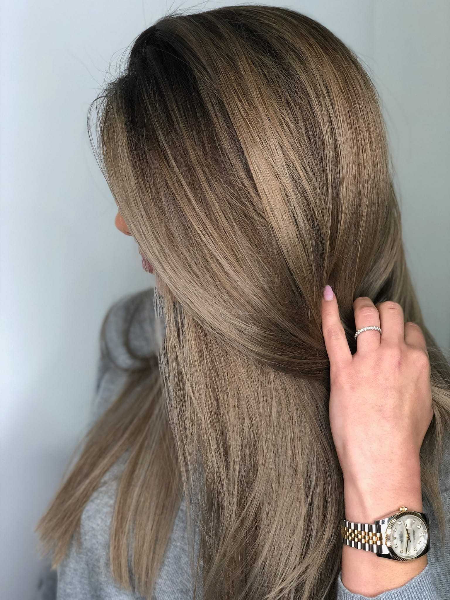 Woman with long, smooth, ash blonde hair, wearing a watch and ring.