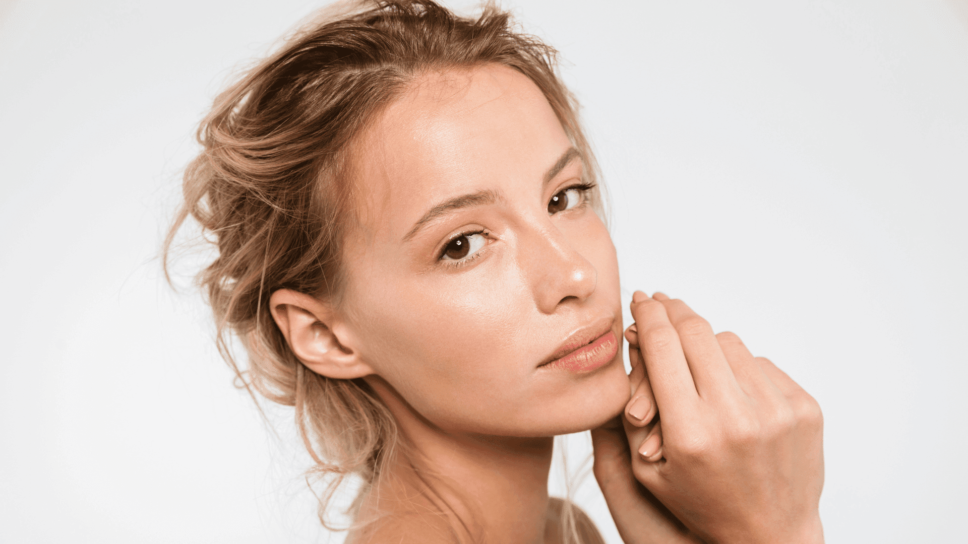 Woman with natural makeup and soft, glowing skin gazing at the camera.