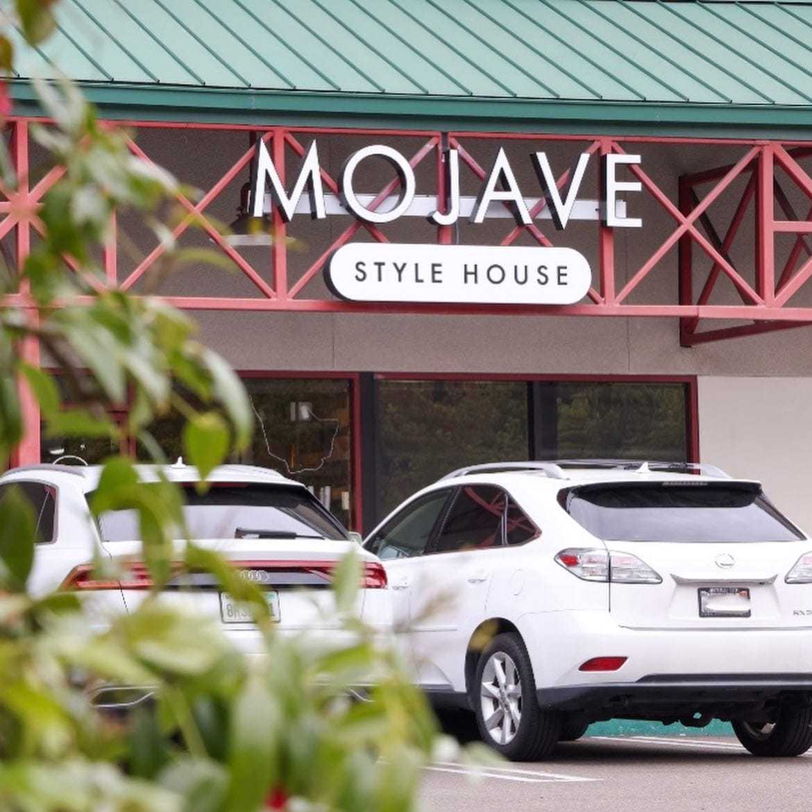 Storefront of Mojave Style House with parked cars in front, green roof and red accents.