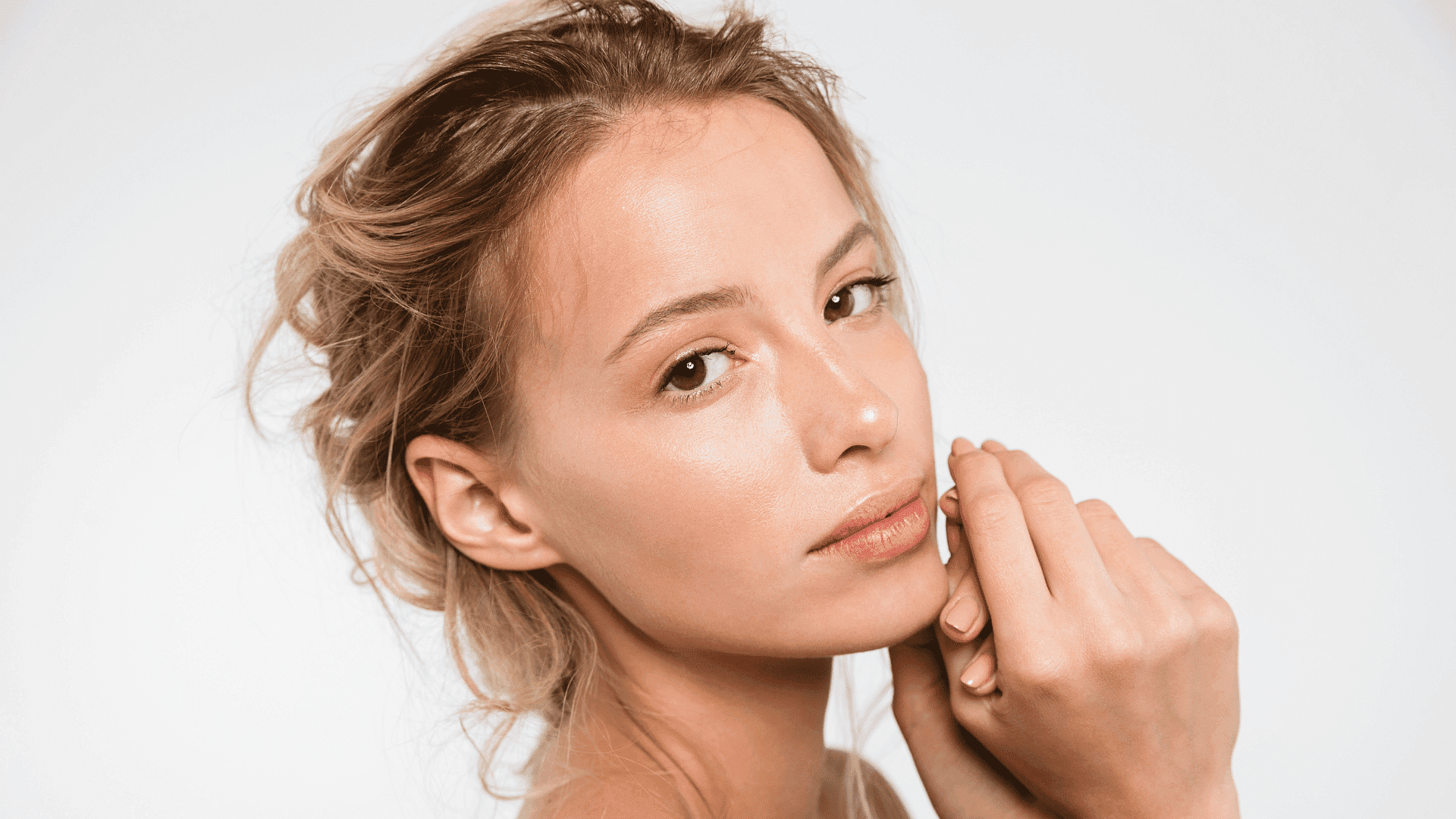 Woman with natural makeup and soft, glowing skin gazing at the camera.