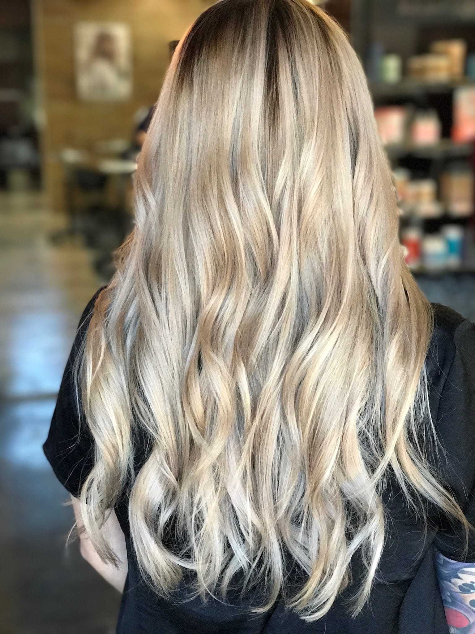 Long, wavy blonde hair styled elegantly from the back in a salon setting.