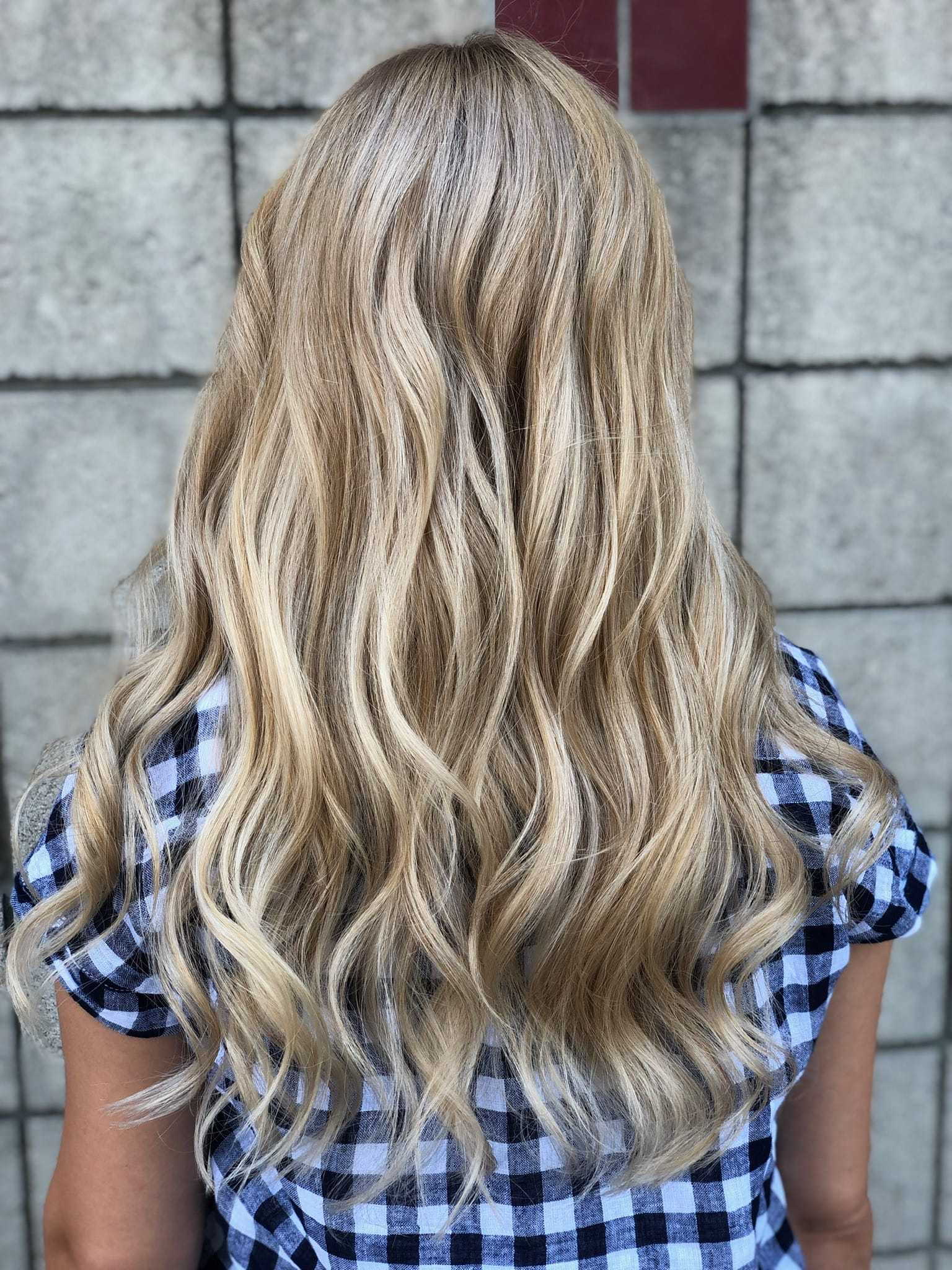 Blonde wavy hair cascading down the back of person wearing a checkered shirt.